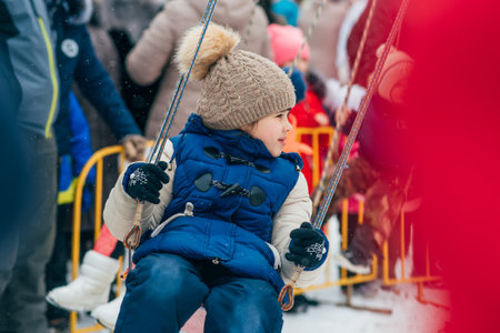 VICHUGA, RUSSIA - FEBRUARY 17, 2018: girl spins on a carousel at the traditional Russian Slavic celebration of the Maslenitsaのeditorial素材