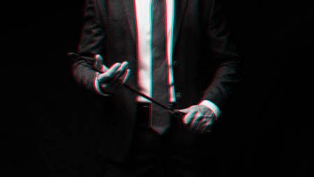 Male dominant businessman in a suit holding a leather whip Flogger for dominationの写真素材