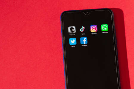 VICHUGA, RUSSIA - FEBRUARY 17, 2021: smartphone with icons of trending social apps on the screen lies on a red background. Logos modern social media on the mobile phoneのeditorial素材