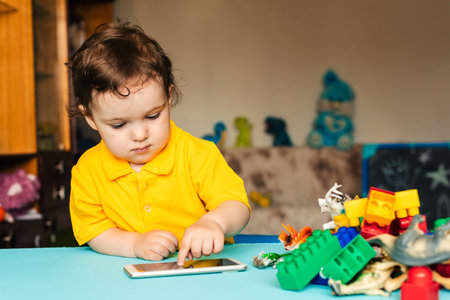 baby boy playing in smartphone against the background of toy