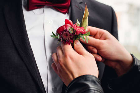 friend puts a boutonniere on the grooms suitの写真素材