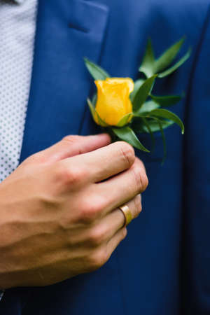 boutonniere of fresh rose flower on the grooms suitの写真素材