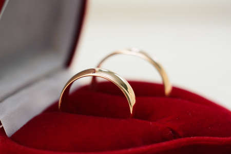 pair of gold wedding rings lie in a red box close-upの写真素材