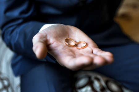 two gold wedding rings in the hands of the manの写真素材