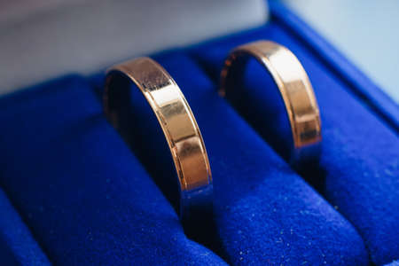 pair of gold wedding rings lies in a blue boxの写真素材