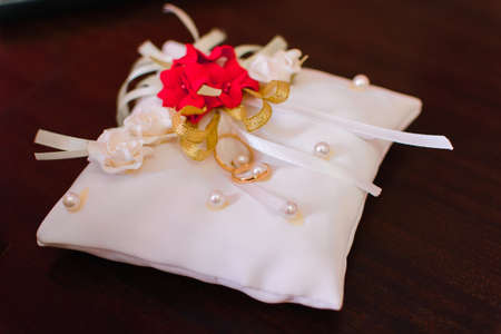 two gold wedding traditional rings on a white cushionの写真素材