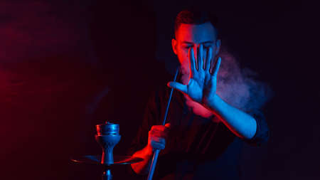 male smoker smokes a hookah in a shisha and lets out a cloud of smoke