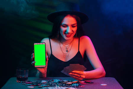 online poker player with a smartphone at a casino table with cards and chips