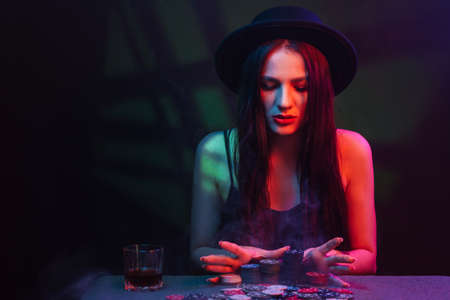 girl plays poker at a table with cards and chips in a casino