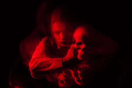 blurry terrible portrait of a ghost witch girl with a dead mans skullの写真素材