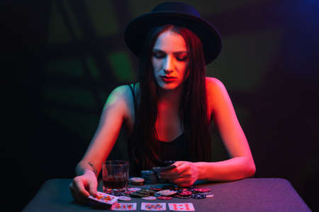 girl plays poker at a table with cards and chips in a casinoの写真素材