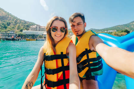 happy man and girl take a selfie riding on sea on banana boat