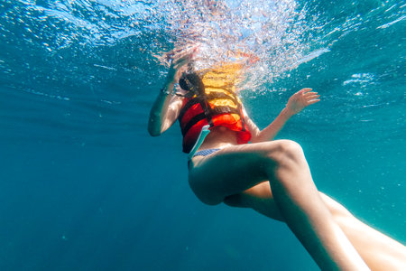 womans body in a life jacket floats underwater in seaの写真素材