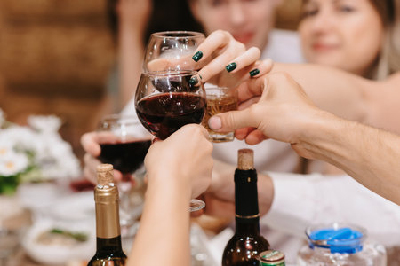 peoples hands clink glasses with alcoholic beveragesの写真素材