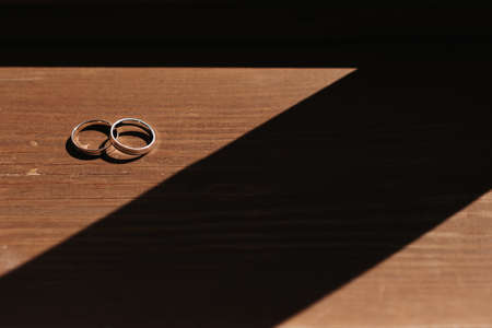 pair of gold engagement rings on a wooden backgroundの写真素材