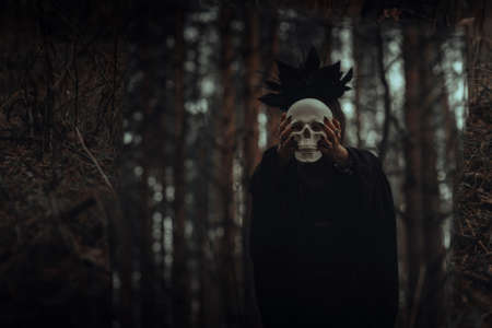 reflection in the mirror of an evil scary witch with a dead mans skull performing mystical occult ritualsの写真素材