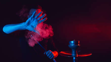 male smoker smokes a hookah in a shisha bar and lets out a cloud of smoke