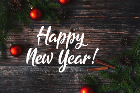 red balls with fir branches on a wooden background and the inscription Happy New Yearの写真素材