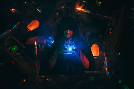 Witcher alchemist makes a secret potion in gloomy laboratory workshop. Magician sorcerer in Halloween costumeの写真素材