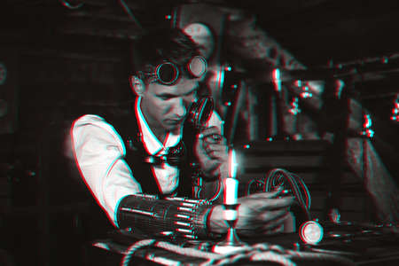 steampunk man in cyberpunk glasses invents mechanisms in a laboratory workshopの写真素材