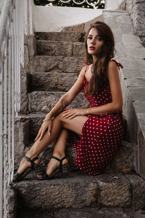 attractive brunette girl with sexy figure poses on a stone staircase on the stepsの写真素材