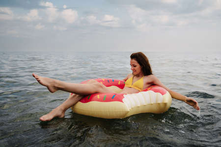 slender girl swims on an inflatable circle in the sea in summerの写真素材
