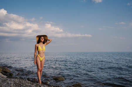 girl in a straw hat on the beach at the sea in summerの写真素材