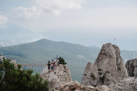 YALTA, RUSSIA - AUGUST 25, 2021: Tourists cross the cliff in the Ai-Petri mountains in Crimea on suspension bridgeのeditorial素材