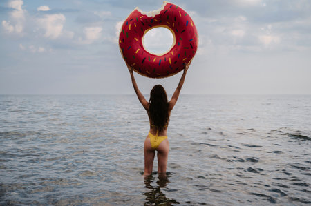 slender girl with a sexy booty in a swimsuit holds an inflatable circle in her hands in the summer...
