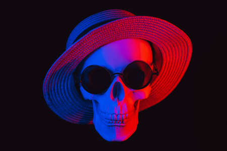 human skull wearing sunglasses and a hat with colored neon lightの写真素材