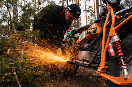 REPUBLIC OF KARELIA, RUSSIA - CIRCA JUNE, 2022: Off-road tournament Ladoga Trophy 2022 around Lake Ladoga. A motorcyclist repairs a motorcycle with a grinderのeditorial素材