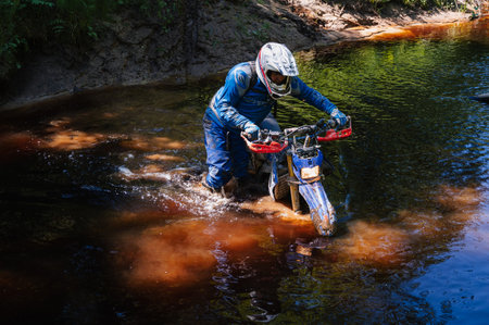 REPUBLIC OF KARELIA, RUSSIA - CIRCA JUNE, 2022: Off-road tournament Ladoga Trophy 2022 in Karelia. Motorcycle racer on an enduro sports motorcycle overcomes a river in a ford during a raceのeditorial素材