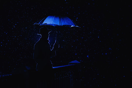 silhouette in the noir style of a male mafia detective in a raincoat and hat under an umbrella