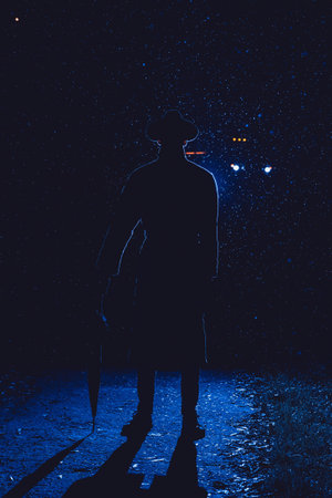 silhouette of a male detective in a hat and raincoat with an umbrella