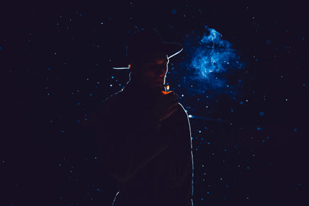 silhouette of a male detective in a hat and raincoat smoking at night