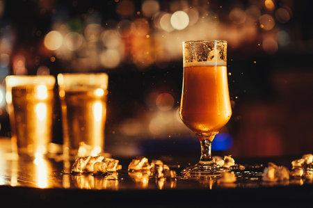 glass of light unfiltered draft beer with on bar counter with drops of sprayの写真素材