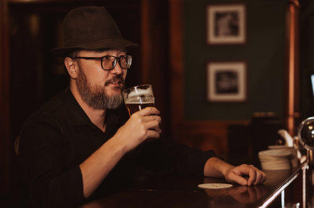 man drinks beer from a glass at bar