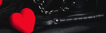 Leather whip and handcuffs for BDSM sex with red hearts as a symbol of Valentines dayの写真素材