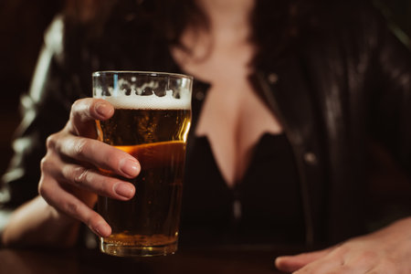 glass of light beer lager with foam in the hand of a womanの写真素材