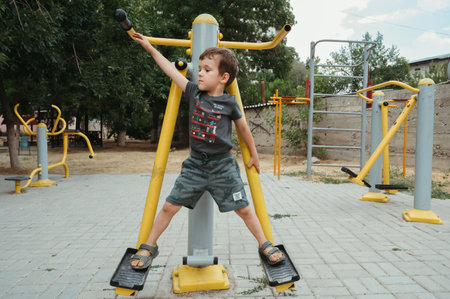 preschooler boy plays on simulators on playground in summerの写真素材