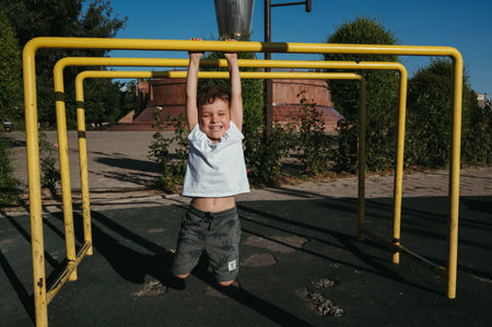 preschool child boy plays on horizontal bars on playground in park in summer