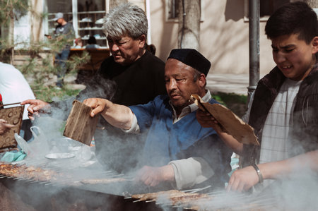 SHYMKENT, KAZAKHSTAN - MARCH 22, 2023: kazakh man cooking barbecue for celebration of Nauryzのeditorial素材