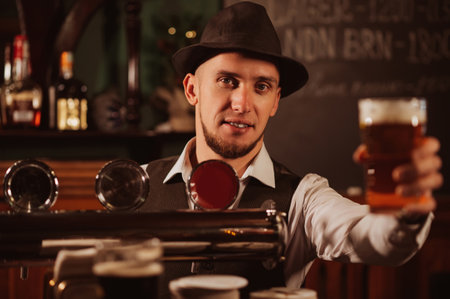 bartender serves in hand a glass of light draft beer lager with foam at bar counter