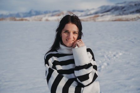 Portrait of a happy Caucasian brunette girl smiling in field with snow in winter