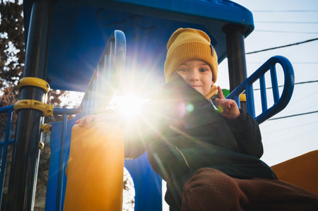 happy child kid boy play on playground on the slide in autumn on a sunny dayの写真素材