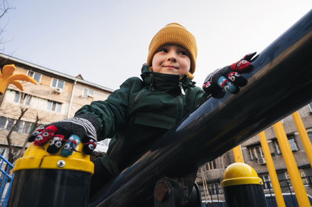 happy child kid boy plays on the horizontal bars on the playground in park in autumnの写真素材