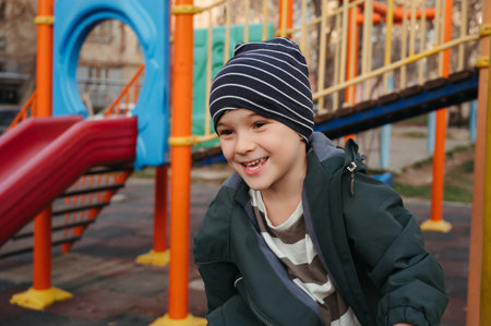 Happy child boy playing on playground in autumn