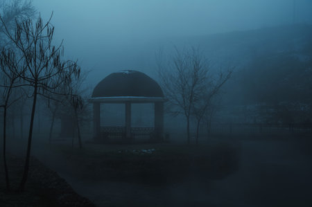 misty landscape with a gazebo by river on an autumn morning in the fog mist