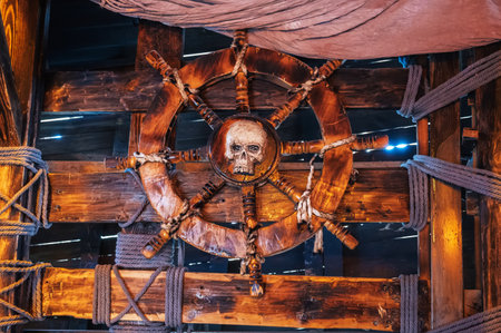 wooden steering wheel with a skull in captains cabin on ancient medieval pirate ship