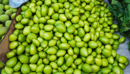 unripe green apricot on counter of a bazaar in Uzbekistan. Traditional Uzbek food on market shelf -...